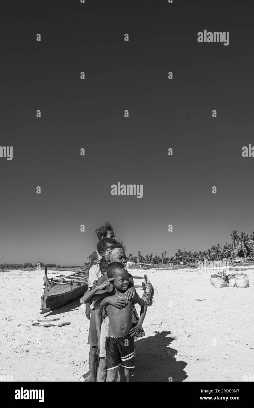 Morondava, Madagaskar - Mai 30,2023: Eine Gruppe von Kindern bleibt in der Schlange am Strand im Hafen von Morondava. Schwarz-weiß Stockfoto