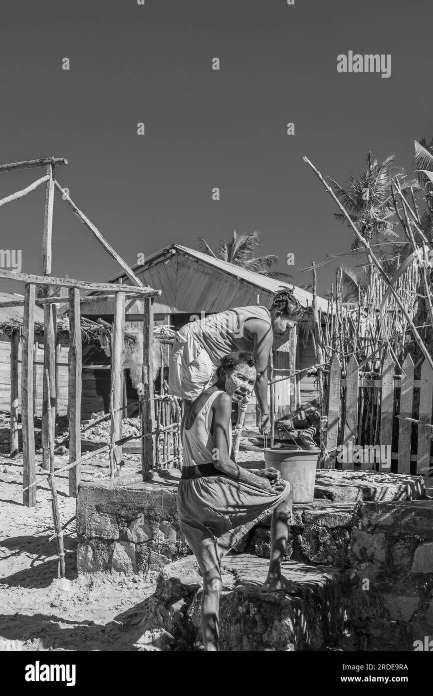 Morondava, Madagaskar - 30,2023. Mai: Zwei madagassische Frauen mit Maskenmalerei, ist bekannt als Masonjaony Wasser aus einem Brunnen in Morondava, schwarz weiß Stockfoto