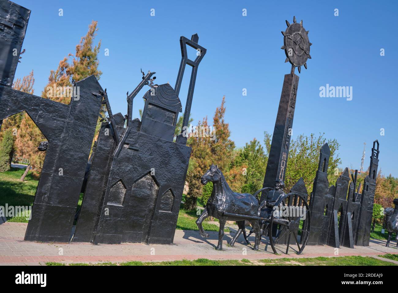 Eine hohe Stele mit Sonnensymbol unter den Wagenfahrern bei der Caravan Silk Road Skulpturenprozession. Im Ethno Historic Complex Park in Shymkent, Kaz Stockfoto