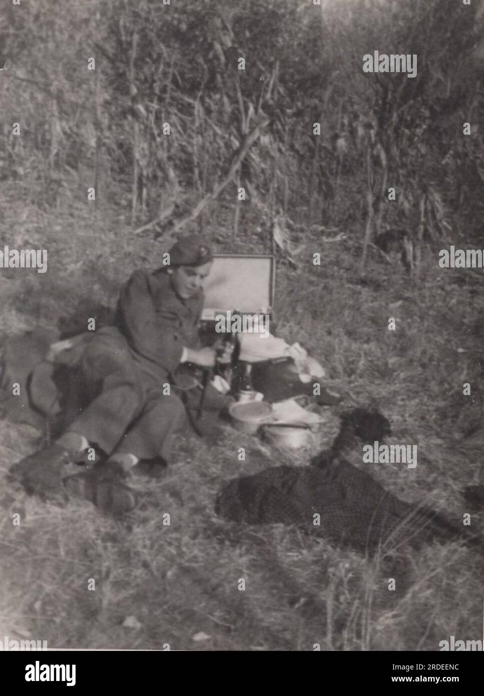 Seltenes Foto des Militärlebens aus dem Zweiten Weltkrieg ( WW2) ein Soldat legt sich auf den Rasen, um sich auszuruhen. Er isst zu Mittag. Essen Sie im Kriegsgebiet kaltes Essen. Stockfoto