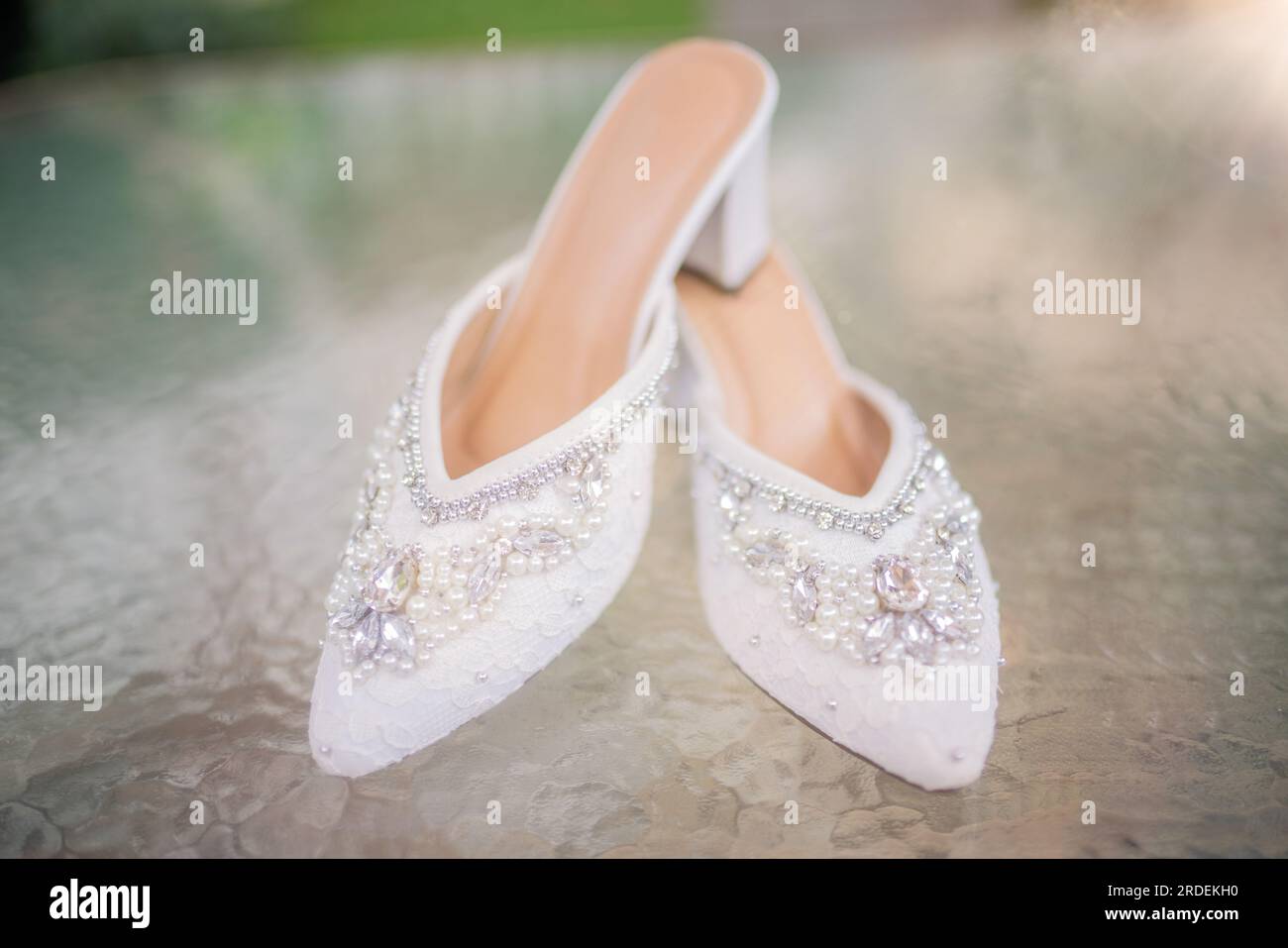 Hochzeitsschuhe mit spitzen Zehen. Schuhe mit hohen Absätzen. Frauenfüße in luxuriösen Sommerschuhen für Damen. Elegante Hausschuhe für Damen auf dem Boden. Fash Stockfoto