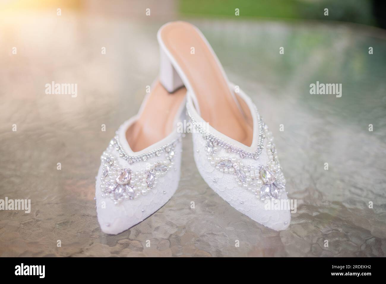 Hochzeitsschuhe mit spitzen Zehen. Schuhe mit hohen Absätzen. Frauenfüße in luxuriösen Sommerschuhen für Damen. Elegante Hausschuhe für Damen auf dem Boden. Fash Stockfoto