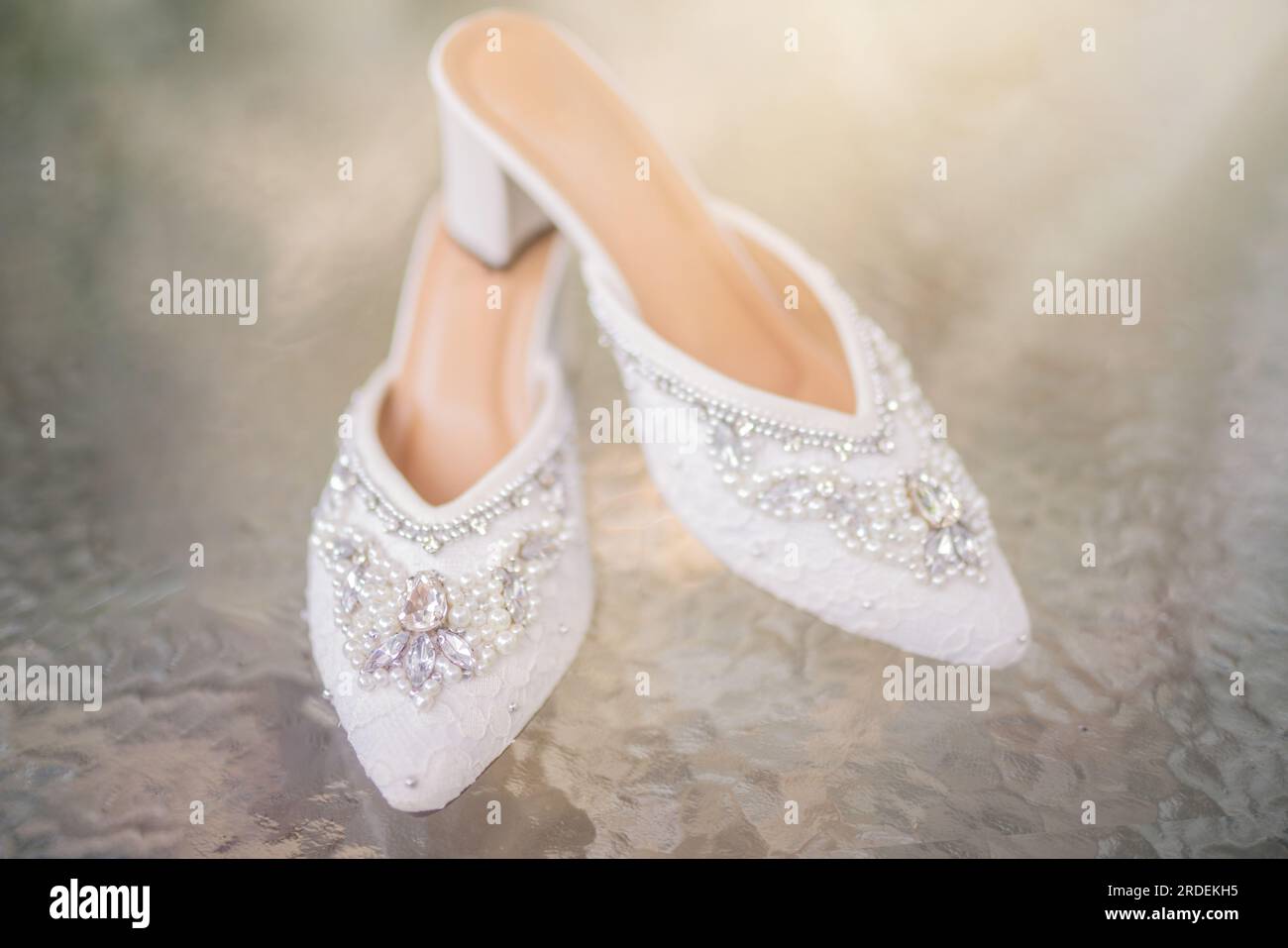 Hochzeitsschuhe mit spitzen Zehen. Schuhe mit hohen Absätzen. Frauenfüße in luxuriösen Sommerschuhen für Damen. Elegante Hausschuhe für Damen auf dem Boden. Fash Stockfoto