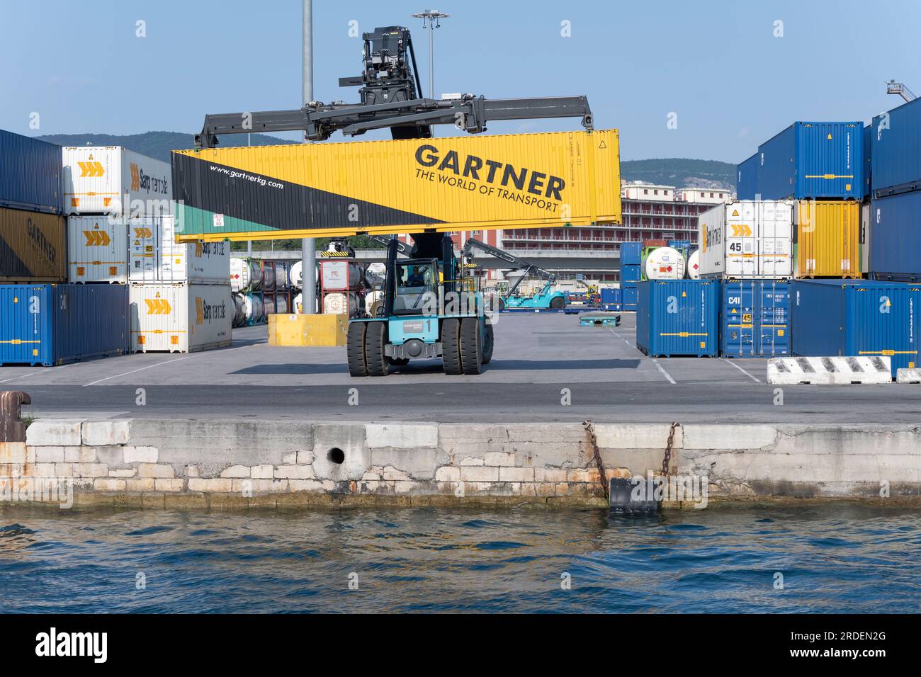 TRIEST, ITALIEN - Mai 29 2023: LKW-Kran mit Containern am Kai, vom Meer aus in hellem Licht am 29. Mai 2023 in Triest, Friuli, Italien Stockfoto