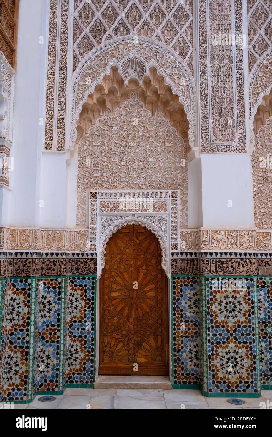 Marokko: Eine Tür in der Ecke des zentralen Innenhofs mit Zellij-Mosaikfliesen auf beiden Seiten und Murqanas-gewölbte Nische oben, Ben Youssef Madrasa (Medersa Ben Youssef), Medina von Marrakesch, Marrakesch. Der Sultan der Saadier-Dynastie, Abdallah al-Ghalib Billah (1517 - 1574), baute die Madrasa im Jahr 1565 (972 AH). Es war einst das größte islamische College im Maghreb (Nordwestafrika). Stockfoto