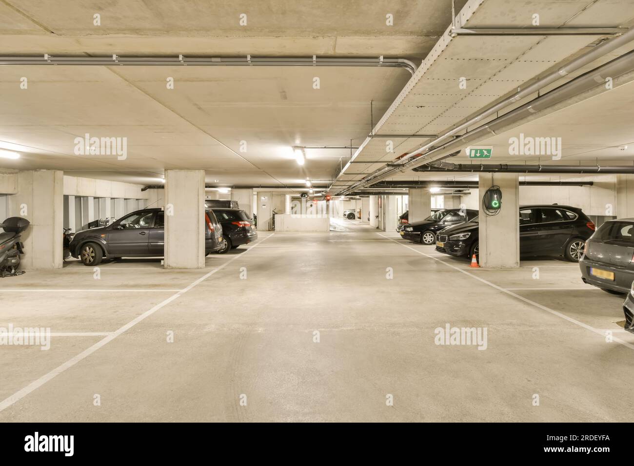 Eine Tiefgarage mit Autos, die in den Garagen geparkt sind und Leute, die auf dem Bürgersteig zu ihren Fahrgeschäften gehen Stockfoto