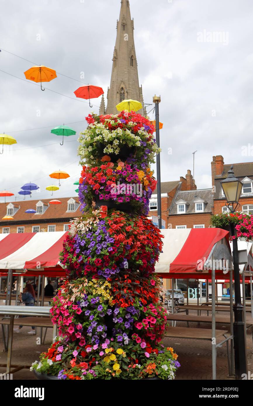 Eine Blumenkolonne auf dem Newark Markt mit Sonnenschirmen und einem Kirchturm im Hintergrund Stockfoto