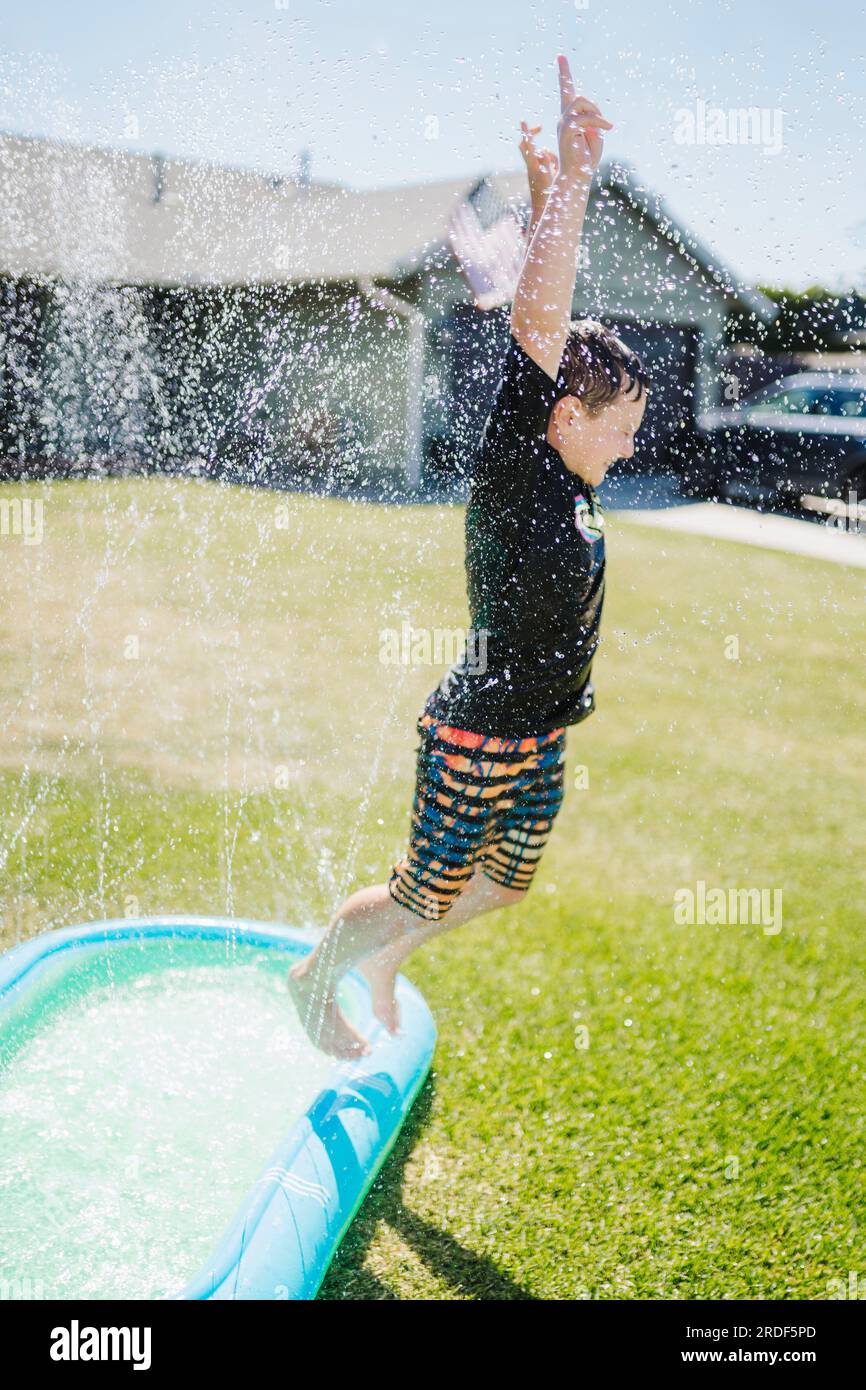 Ein Junge springt im Garten aus dem Pool Stockfoto