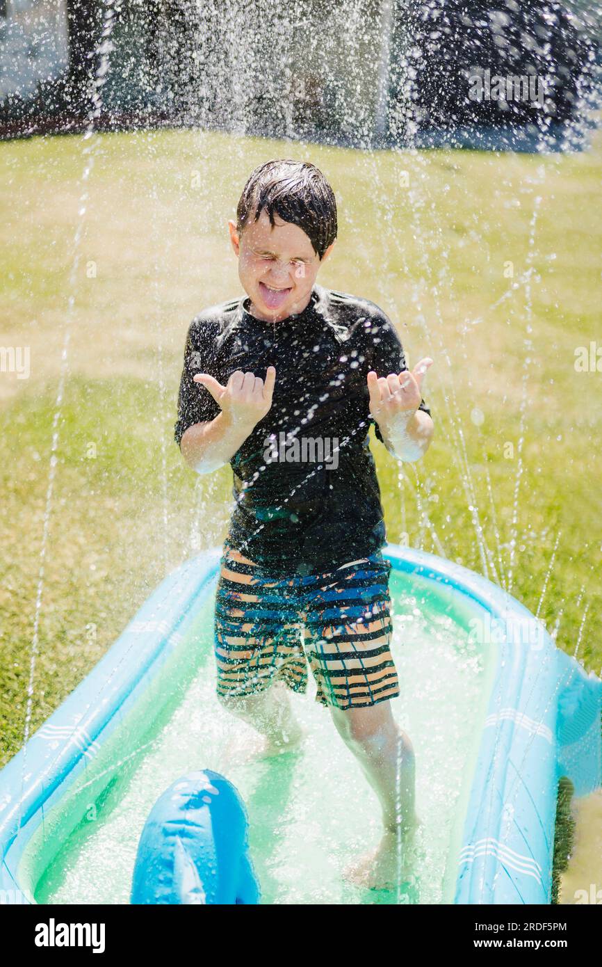 Ein Junge, der im Sommer mit einem Sprinkler spielt Stockfoto