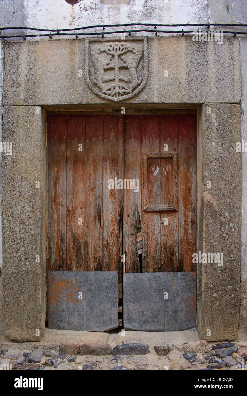 Castelo de Vide, Portugal. Massiver steingerahmter Eingang zum Haus in der Altstadt - alte Holztür, Wappen in Steinlintel geschnitzt. Stockfoto