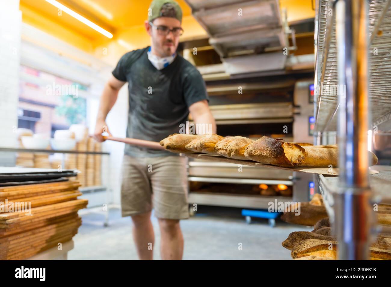 Bäckerei in der Kunsthandwerkstatt, die die Brotlaibe des Ofens auf die Regale stellt Stockfoto