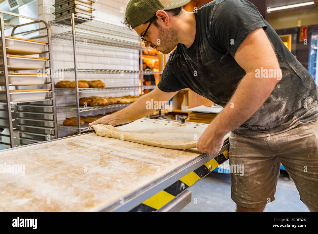 Der Mitarbeiter stellt das Brot in einer Kunsthandwerkstatt vor den Ofen Stockfoto