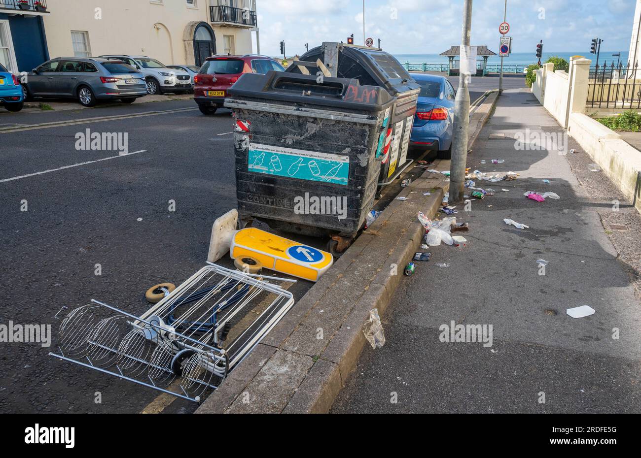 Müll, einschließlich eines Hinweisschilds in Richtung Verkehr, links auf der Brighton Street bei den öffentlichen Mülltonnen, Sussex, England UK Stockfoto