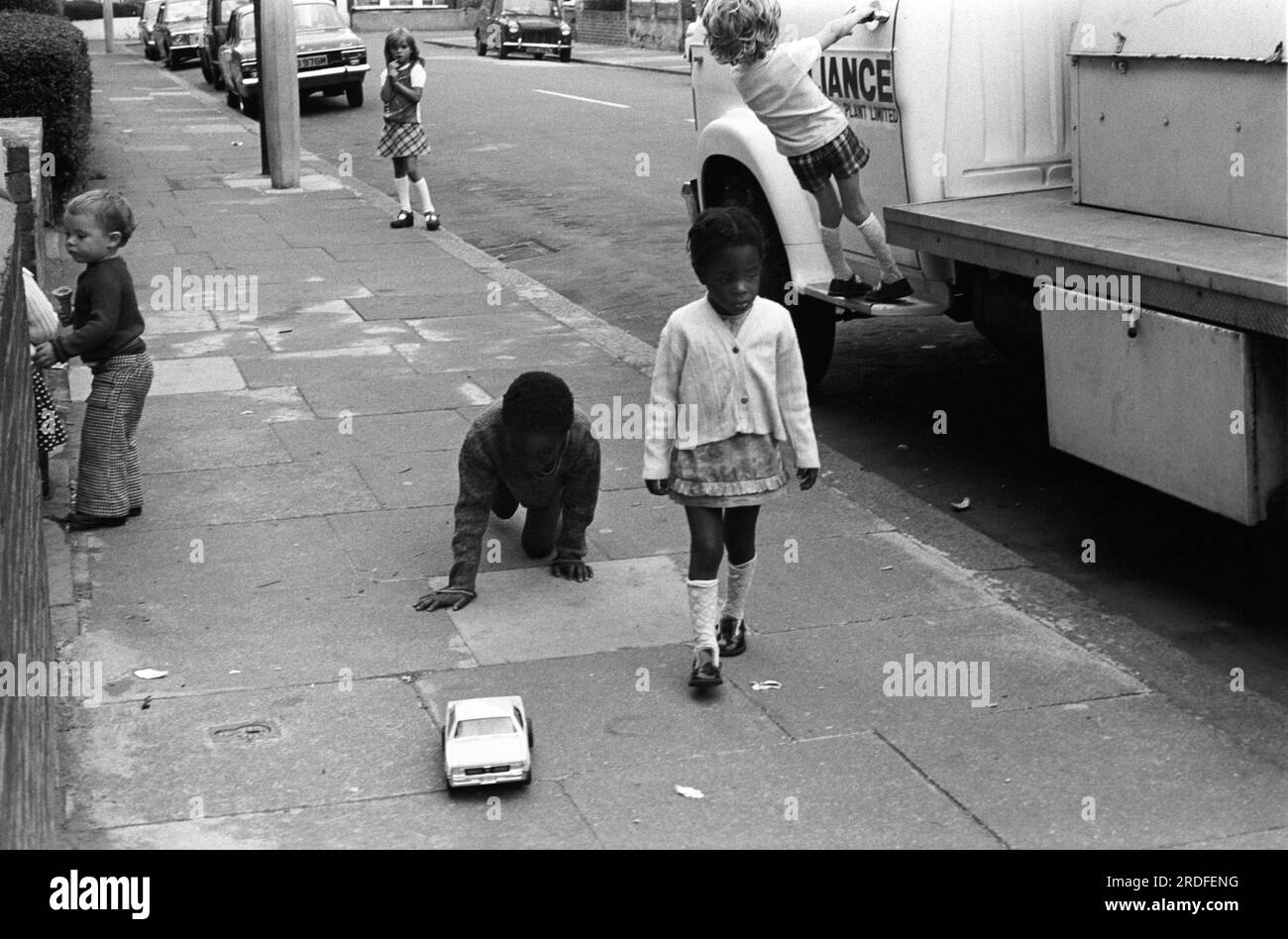 Kinder spielen in der Street 1970er UK. Kinder außerhalb ihres Familienhauses mit einem großen Topauto. Eine ethnisch vielfältige Gruppe glücklicher, sicherer Kinder. Elefant und Castle, London, England, um 1975. HOMER SYKES aus Großbritannien Stockfoto