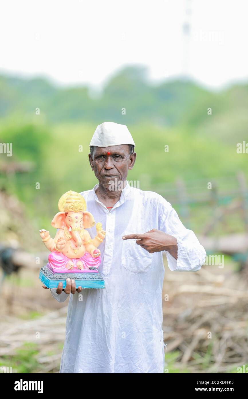 Ein alter indischer Mann, der Lord Ganesha Idol in den Händen hält, ein glücklicher, alter, armer Mann Stockfoto