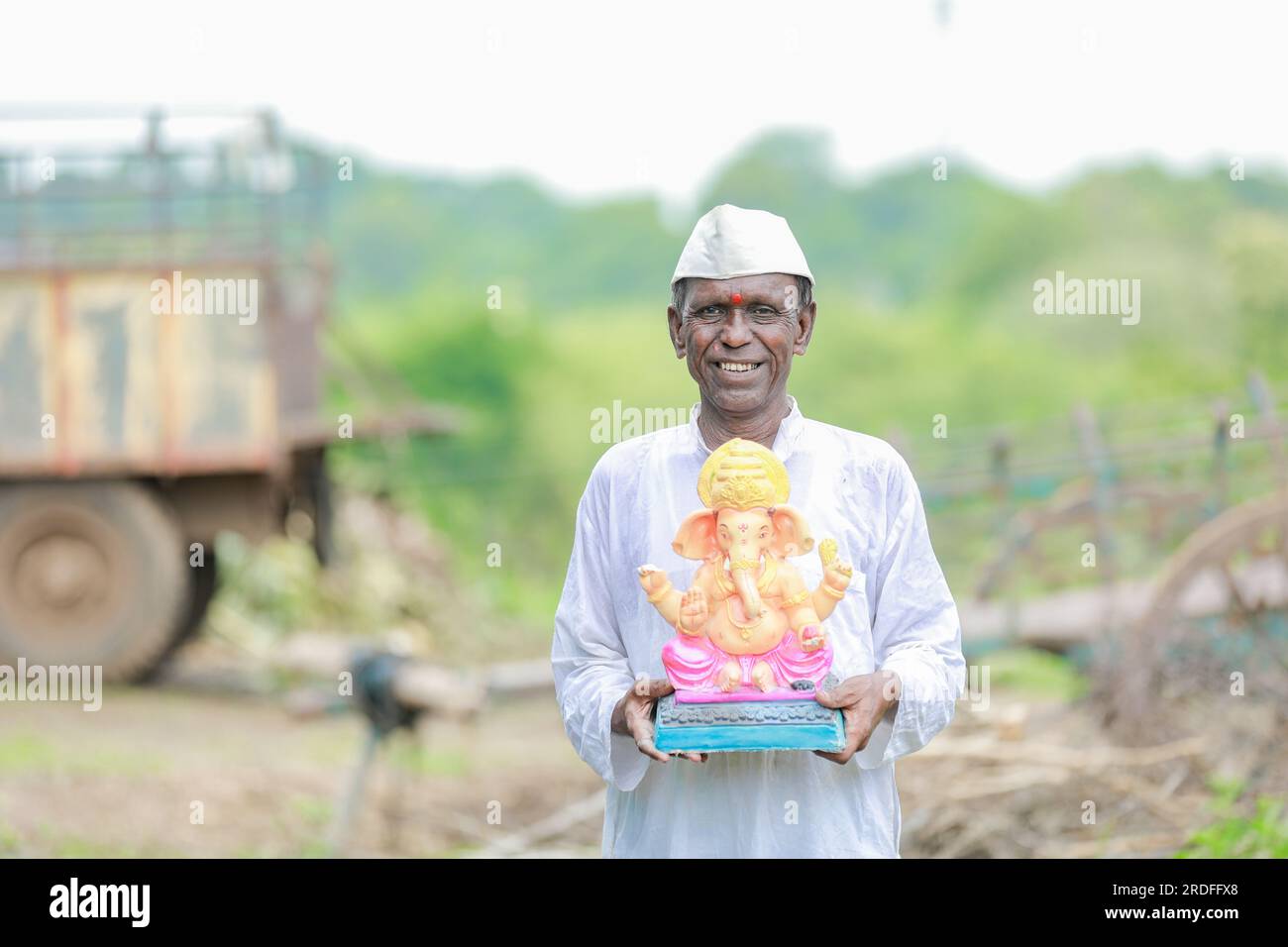 Ein alter indischer Mann, der Lord Ganesha Idol in den Händen hält, ein glücklicher, alter, armer Mann Stockfoto