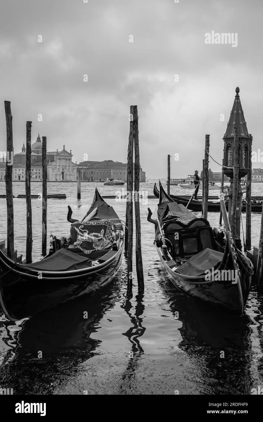 Venedig, Italien - 27. April 2019 : Ein hölzerner Pier mit einer Laterne, Gondeln und einem Gondoliere im Hintergrund in Venedig, Italien Stockfoto