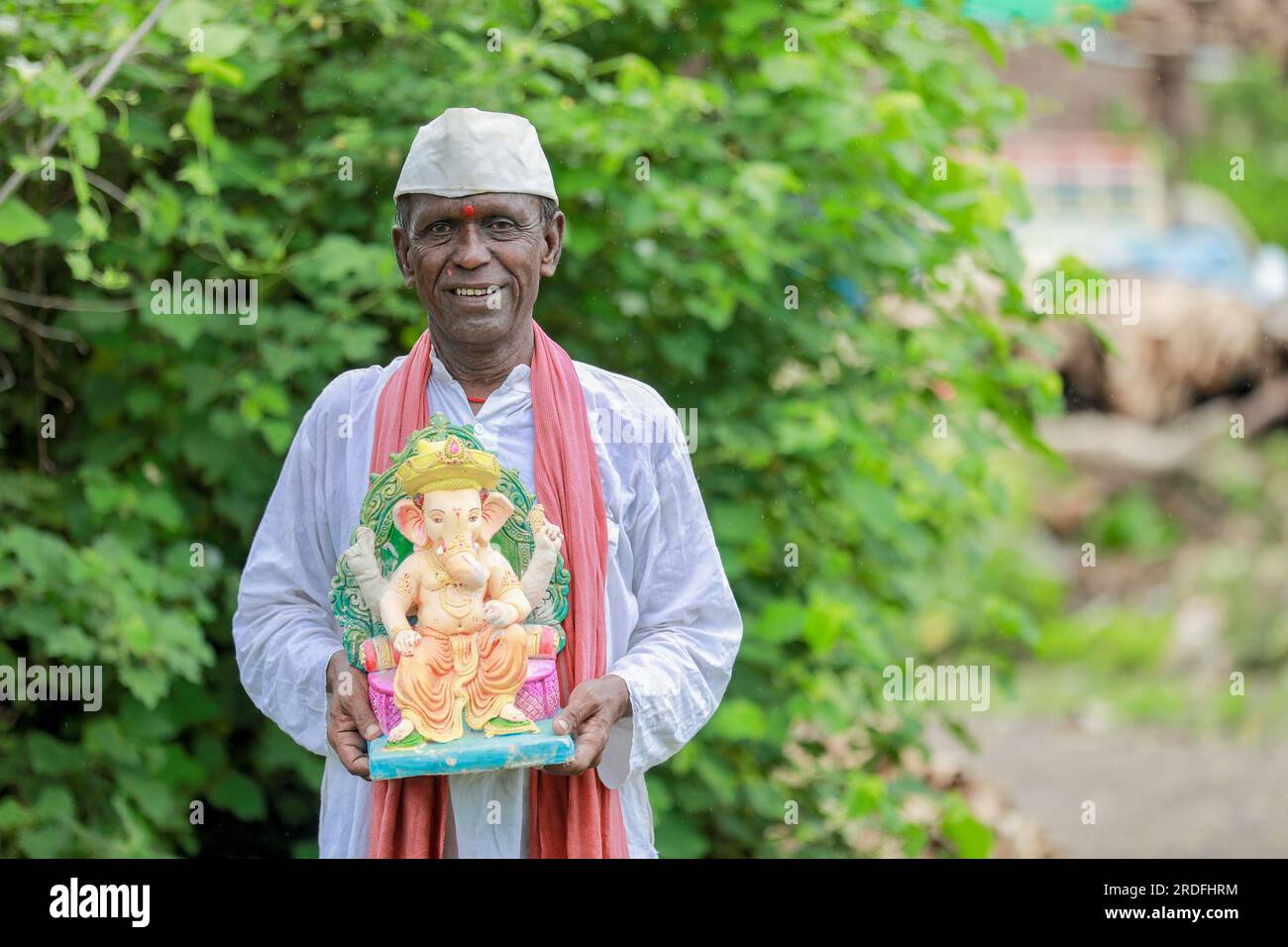 Ein alter indischer Mann, der Lord Ganesha Idol in den Händen hält, ein glücklicher, alter, armer Mann Stockfoto