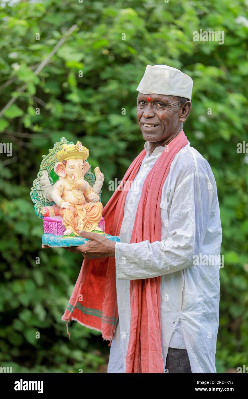 Ein alter indischer Mann, der Lord Ganesha Idol in den Händen hält, ein glücklicher, alter, armer Mann Stockfoto
