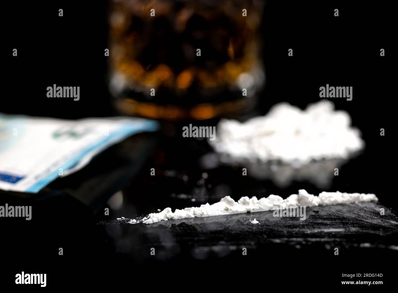 Eine Linie weißes Kokain, ein Glas Rum und Geld Stockfoto