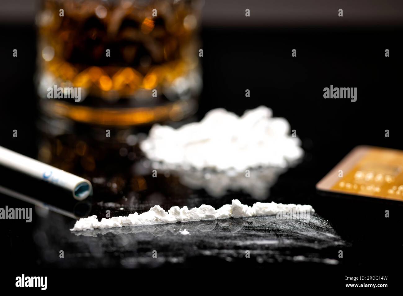 Weiße Kokainlinie, goldene Kreditkarte und Glas mit Rum Stockfoto