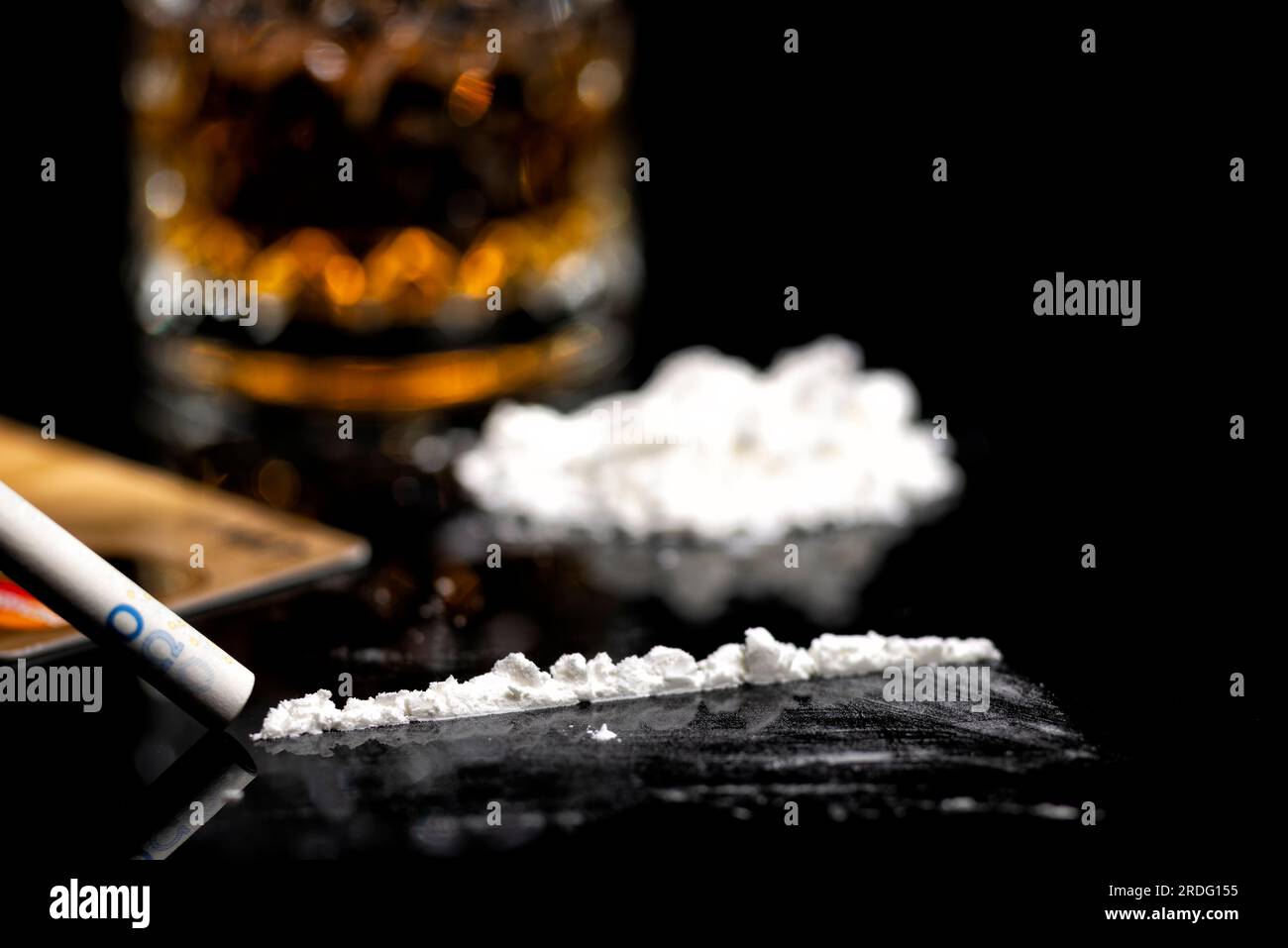 Weiße Kokainlinie, goldene Kreditkarte und Glas mit Rum Stockfoto