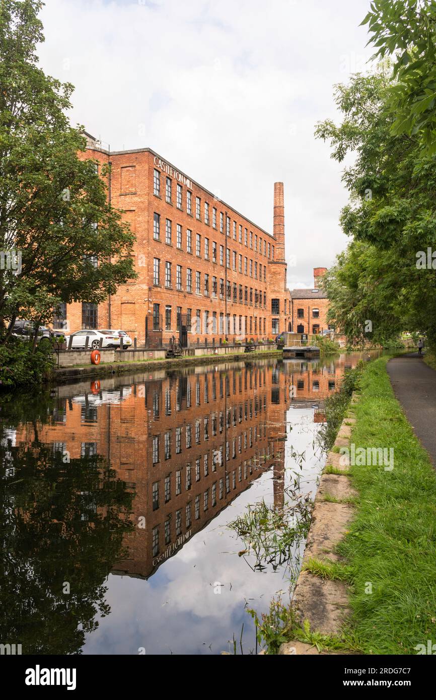 Das denkmalgeschützte Castleton Mill-Gebäude spiegelt sich im Leeds und Liverpool Canal in Leeds, England, UK, wider Stockfoto