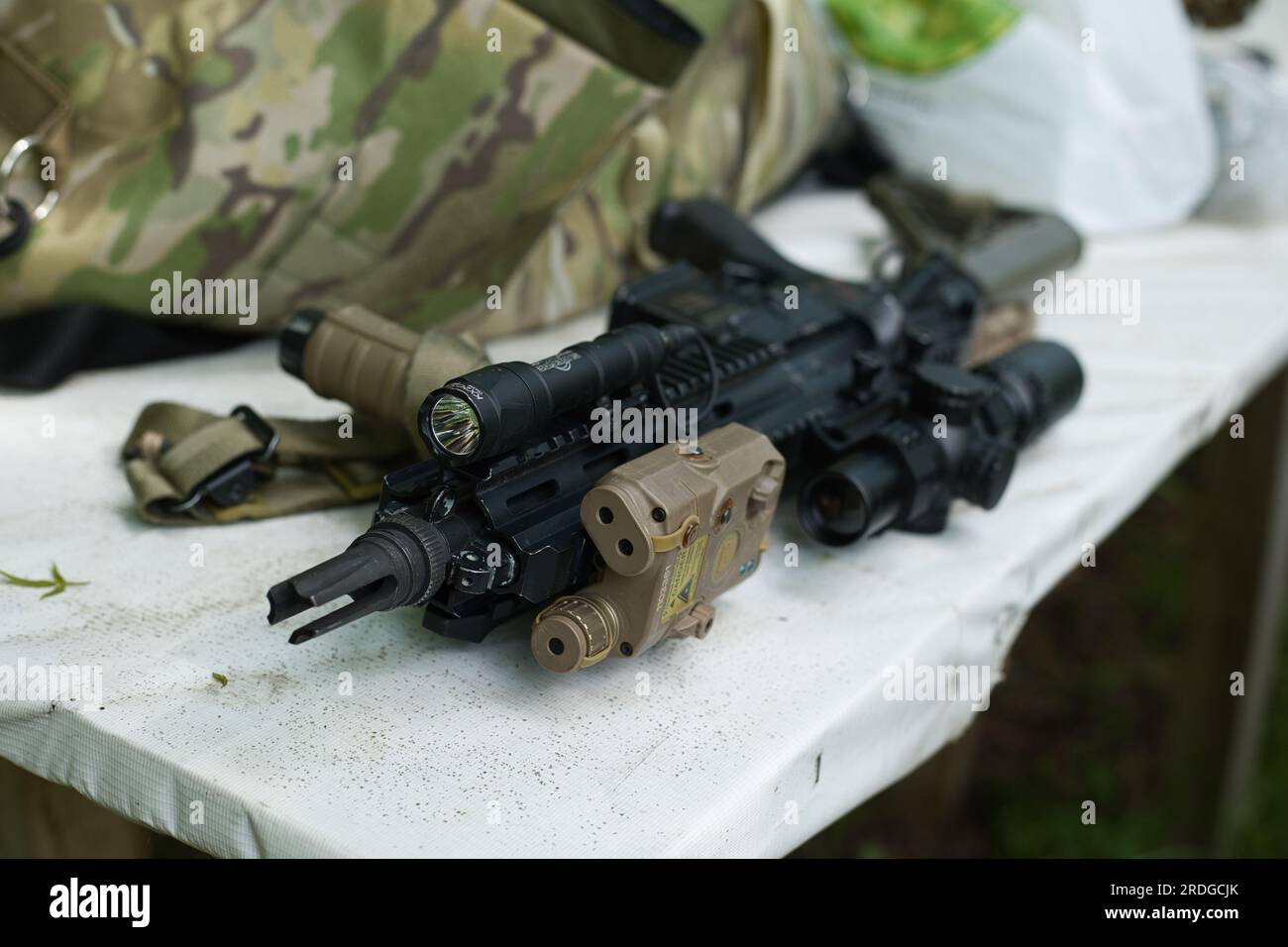 airsoft-Waffe HK416, schwarze Waffe auf dem Tisch mit einer Taschenlampe Stockfoto