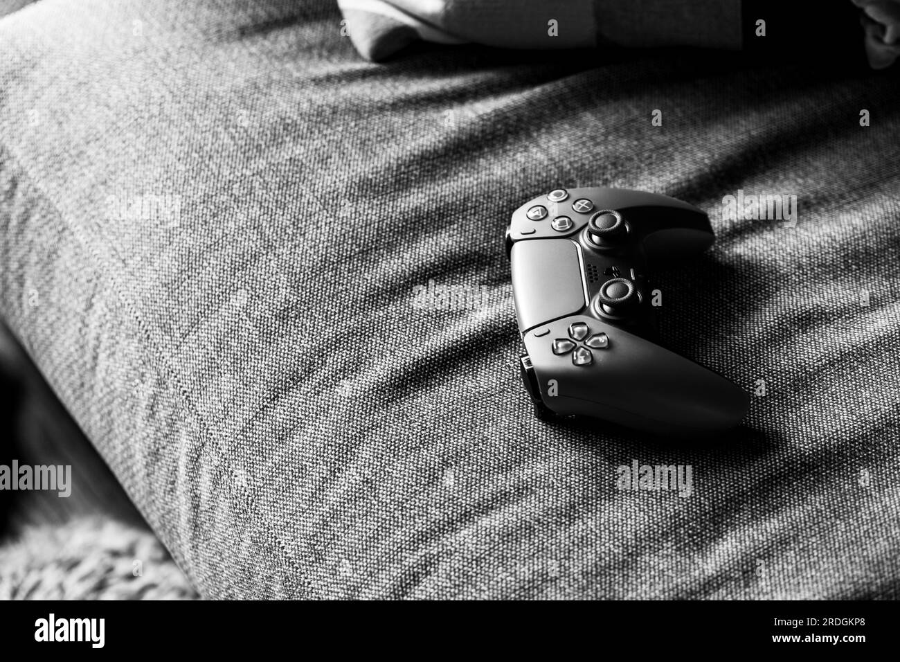 Brecht, Belgien - 14. juli 2023: Schwarz-weißes Porträt eines traditionellen offiziellen playstation 5 -Game-Controllers, der auf einer Couch liegt und gespielt werden kann Stockfoto