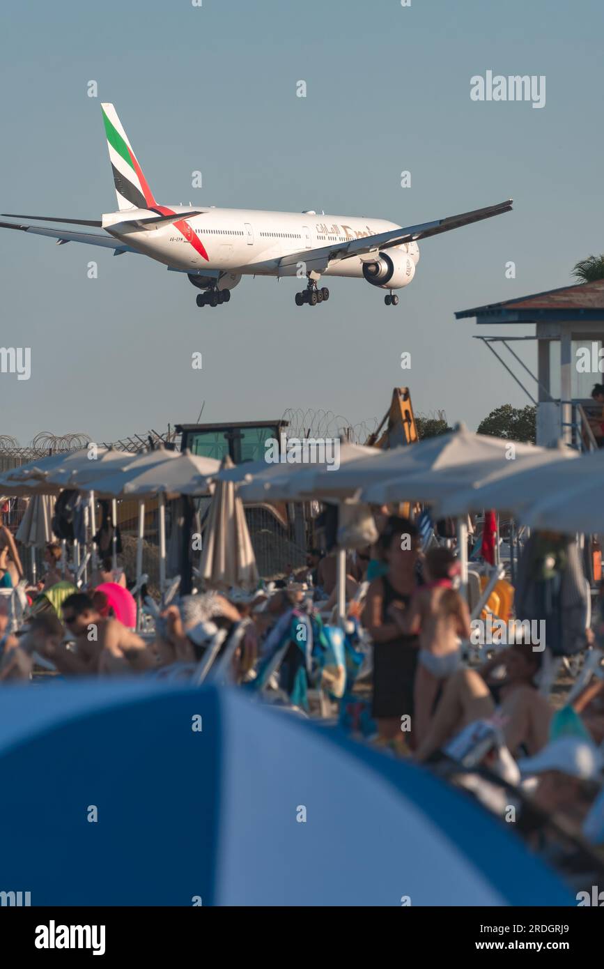 Larnaca, Zypern - 17. Juli 2022: Boeing 777-31H(er) der Emirates Airlines landen über dem überfüllten Mackenzie Beach am Flughafen Glafcos Clerides Stockfoto