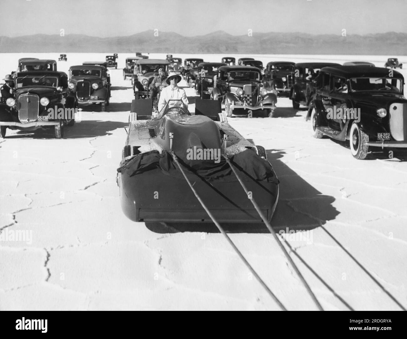 Bonneville Salt Flats, Utah: 3. September 1935 Sir Malcolm Campbells Bluebird Rennwagen wird für seinen ersten Probelauf auf die Salzberge gezogen, um einen neuen Geschwindigkeitsrekord von 300 km/h zu erreichen. Die große Autoseskorte ist im Hintergrund. Stockfoto