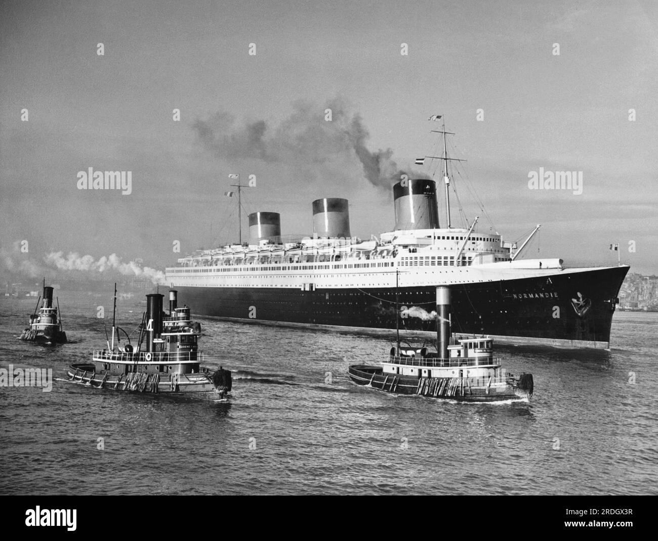 New York, New York: 16. März 1937 das französische Schiff „Normandie“, begleitet von Schleppbooten, die sich ihrem Pier im Nordfluss nähern. Stockfoto