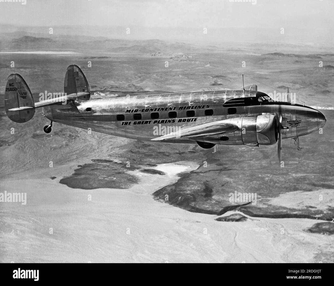 Vereinigte Staaten: c. 1942 A Mid-Continent Airlines Lockheed L-18 Lodestar im Flug über Wüstengelände, dieser Betreiber war der erste, der diese Art von Flugzeugen im Jahr 1942 einsetzte. Stockfoto
