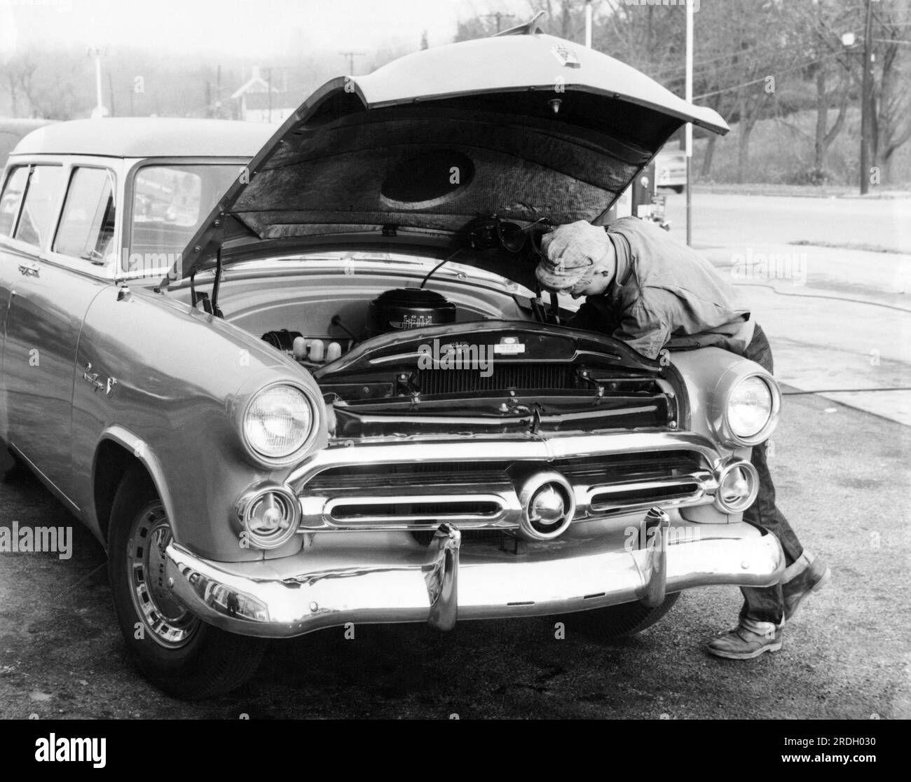 USA: ca. 1952 Ein Mann repariert seinen 1952 Ford Ranch Wagon am Straßenrand. Stockfoto