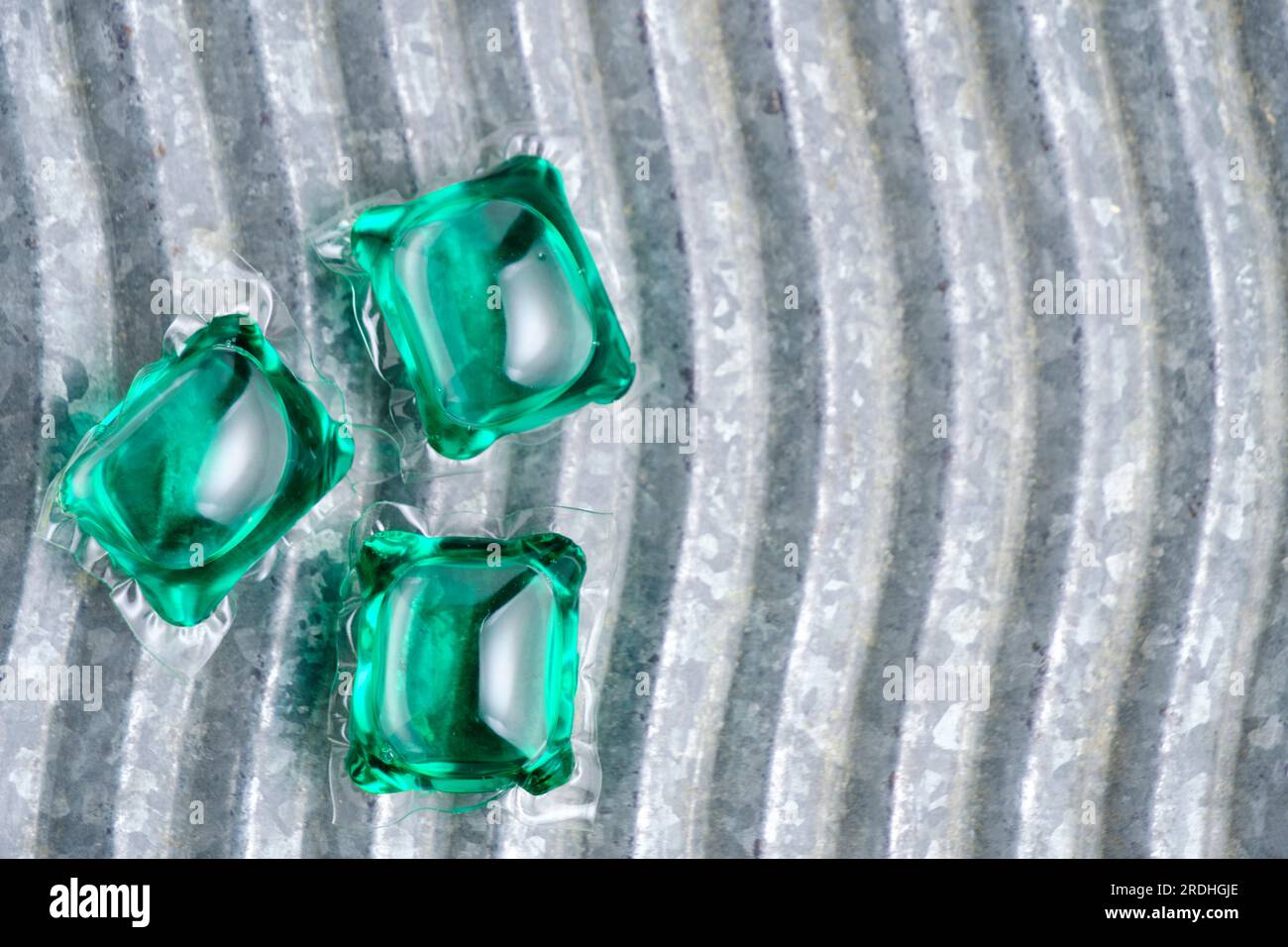 Grüne Kapseln zum Waschen auf dem Hintergrund-Waschbrett Stockfoto