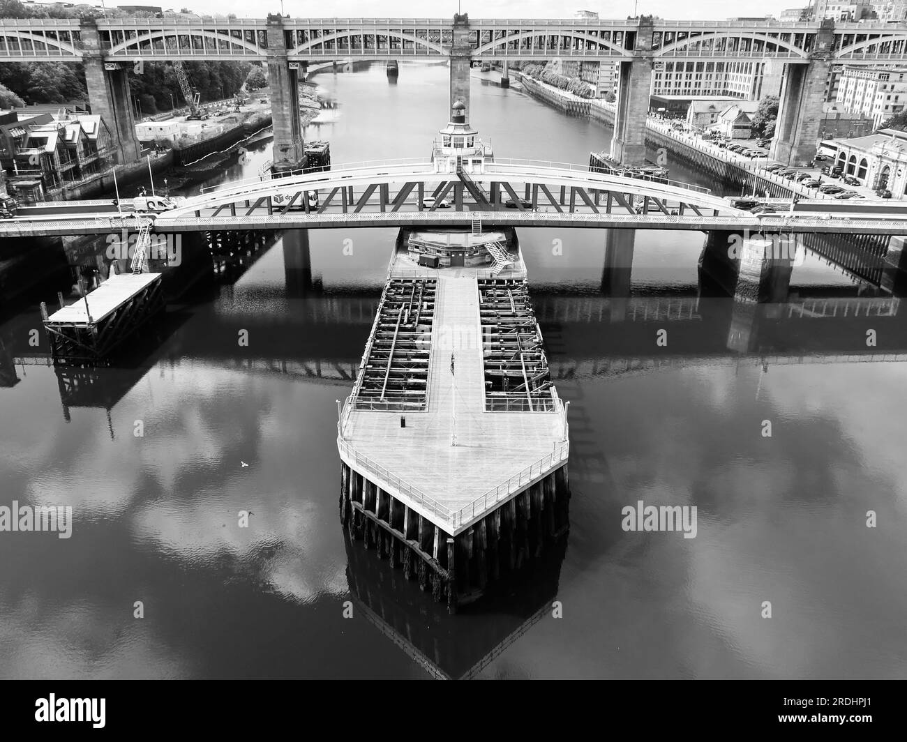 Newcastle, Vereinigtes Königreich - 20. Juli 2023 : Mono image. Schwenkbrücke und Anlegestelle im Vordergrund. Hohe Straßen- und Eisenbahnbrücke im Hintergrund. Fluss Tyne. Stockfoto