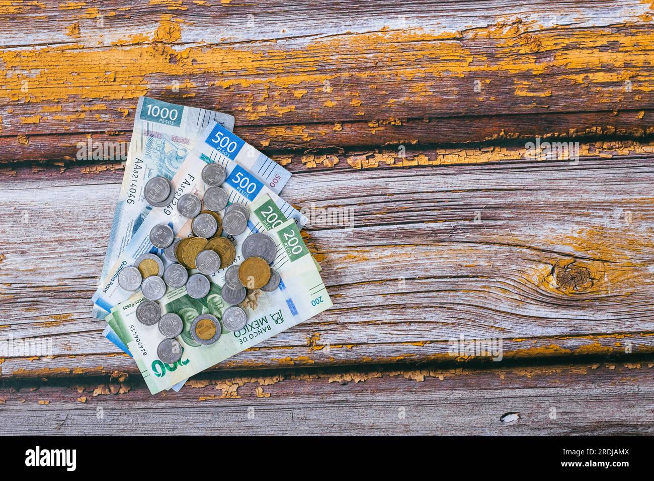 Ein Stapel mexikanischer Münzen und Scheine auf einem Holztisch. Stockfoto