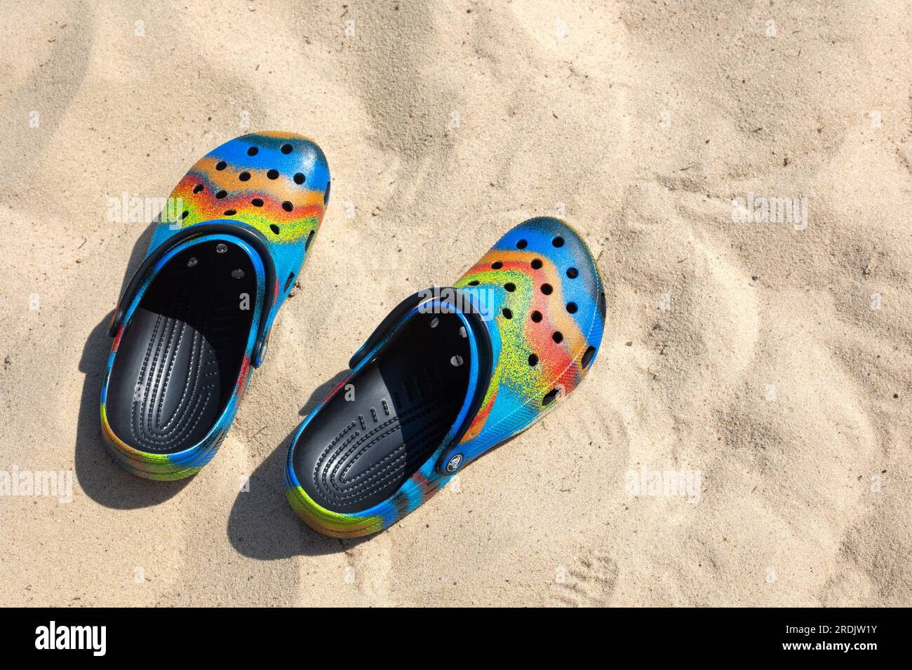 Ukraine, Kiew - Juli 04. 2022: Сolorful Crocs Schuhe am Strand, Urlaubshintergrund. Сolorful trendige Croc Strandschuhe. Urlaubskonzept. Fahrbewegung V Stockfoto
