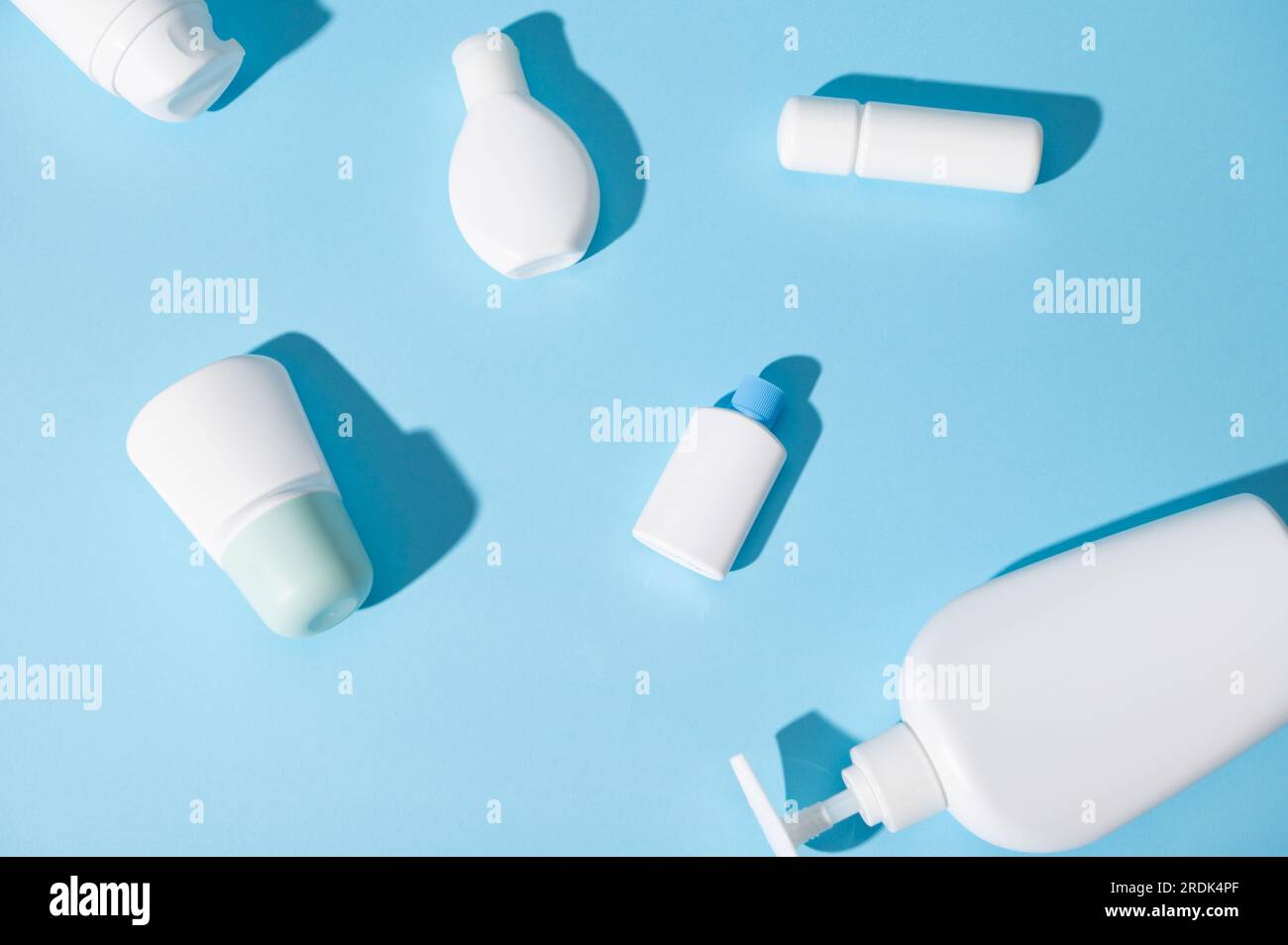 Stillleben mit Modell-Tester-Flaschen für Markenverpackung und Design, mit Kosmetikprodukten für Haut- und Körperpflege, Anzeige auf isolierten blauen s. Stockfoto