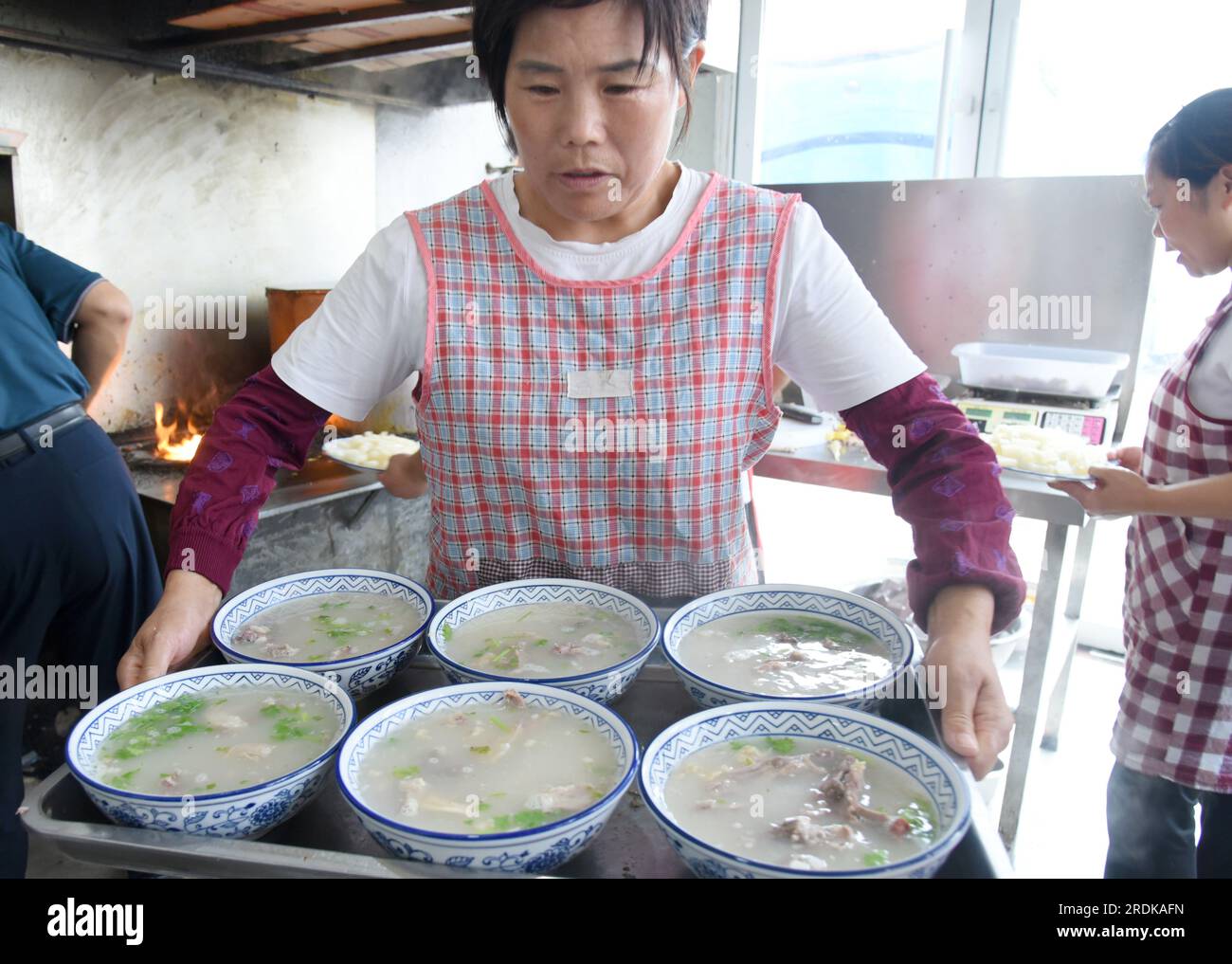 ZAOZHUANG, CHINA - 22. JULI 2023 - Ein Kellner serviert Hammelsuppe in einem Restaurant für Lammsuppen in Xiji, Shanting, Zaozhuang, Ostchina Stockfoto