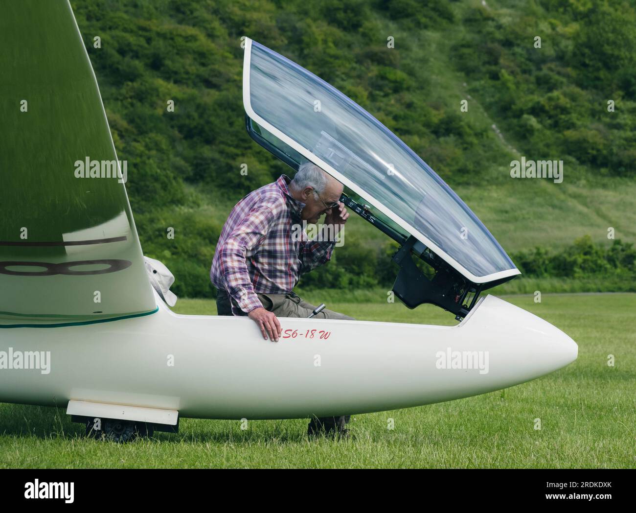 Ein Mann überprüft die Zifferblätter und den Zustand seines Glider-Flugzeugs auf einer Landebahn in England Stockfoto