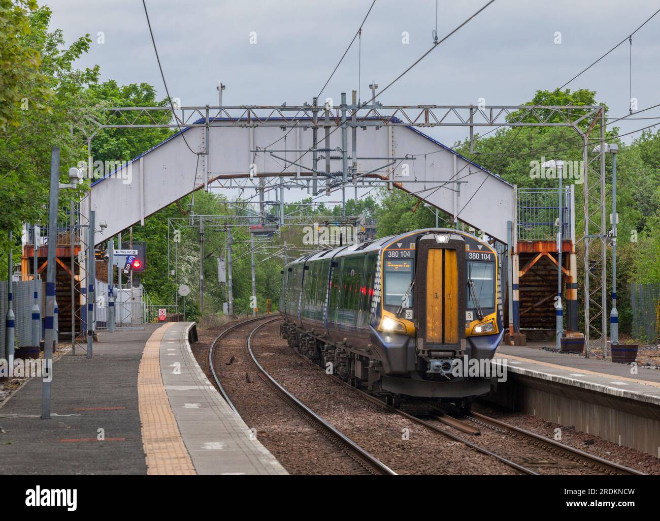 ScotRail Siemens Klasse 380 elektrischer Mehrzweckzug, der am Bahnhof Paisley St James ankommt, mit der Fußgängerbrücke über den Gleisen Stockfoto