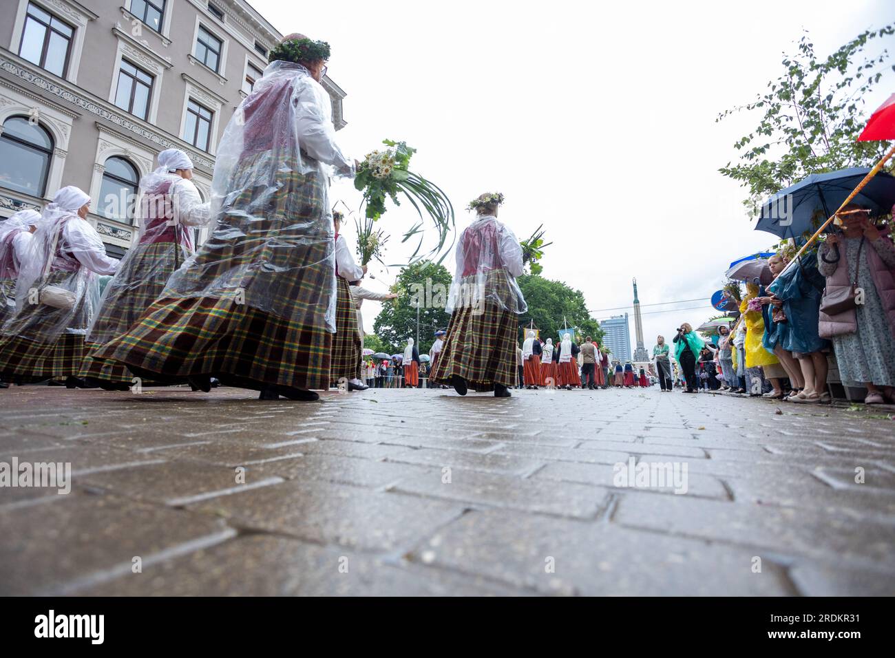 Teilnehmer in traditionellen Trachten gehen während der Eröffnungsparade des Nationwide Lettischen Song- und Tanzfestivals in Richtung des Freedom Monument Stockfoto