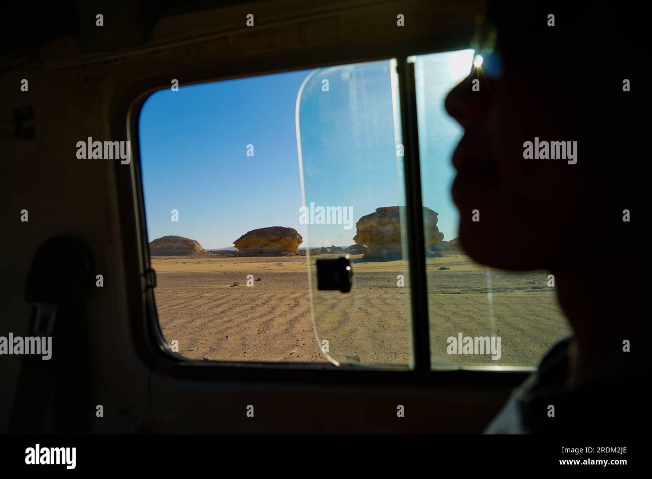 Ein Blick auf die Weiße Wüste aus dem Fenster eines 4x4 Jeeps in Ägypten. Von der Erosion von Vulkanen und einem Quarzberg bis hin zu verwitterten Felsen und weißen Kreidefelsen ist die Schwarze und Weiße Wüste Teil der Frarafra-Depression in der Sahara und liegt im westlichen Teil Ägyptens. Die weite Wüste führt zu den Hauptstraßen in der Nähe der libysch-ägyptischen Grenze, wo sie jetzt mit militärischer Präsenz schwer bewaffnet ist. Die bizarre natürliche Landschaft, die vor Millionen Jahren von einem Meeresboden aufstieg, ist jetzt mit Karstkalkstformationen übersät, die der Oberfläche anderer Planeten in der Uni ähneln Stockfoto