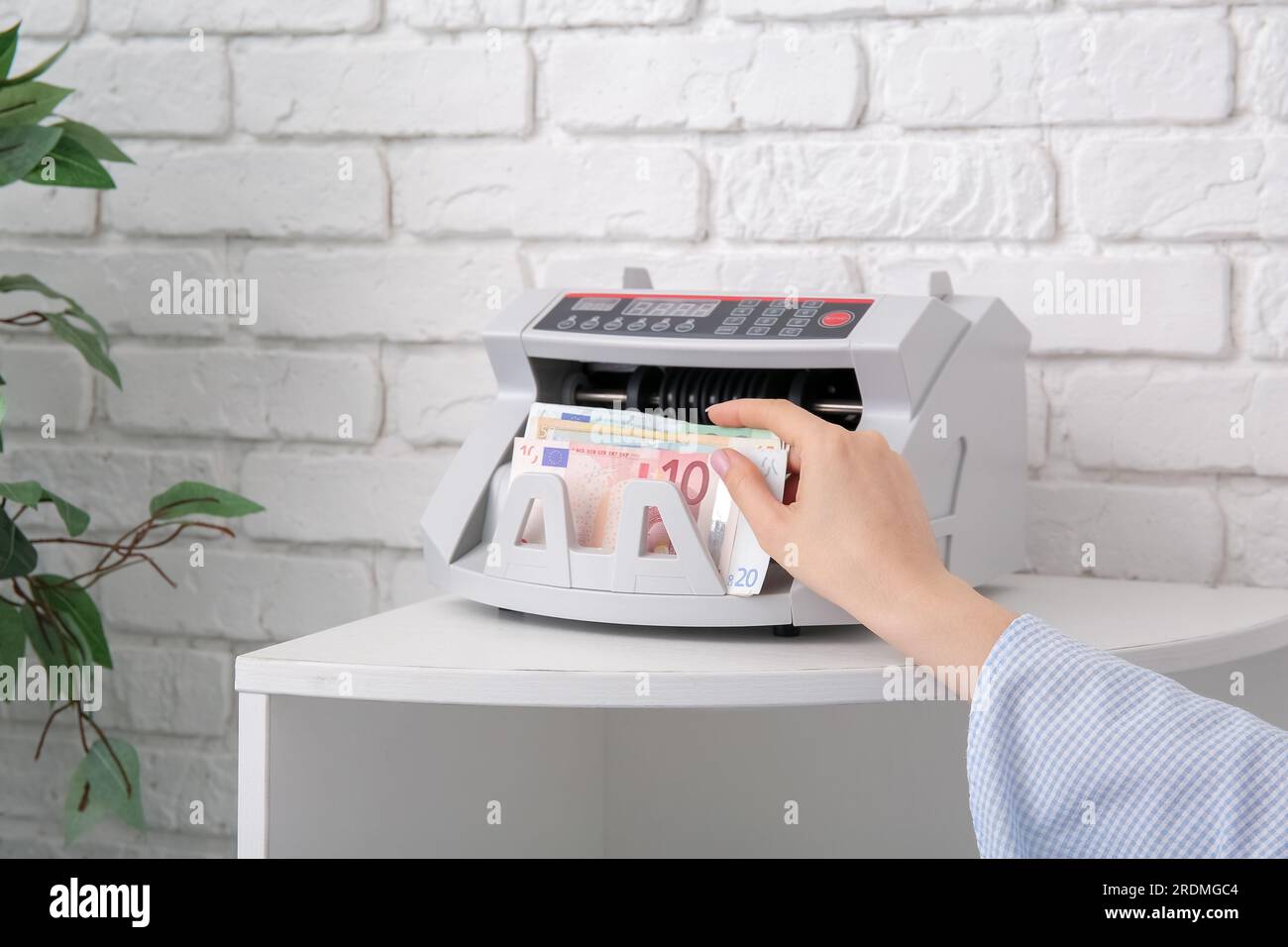 Frau, die Euro-Banknoten in einen Geldzähler im Regal im Büro einlegt Stockfoto