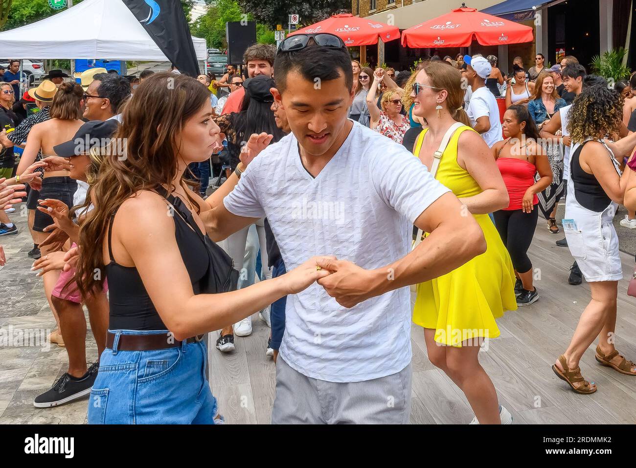 Toronto, Kanada - 19. Juli 2023: Ein tanzendes Paar inmitten anderer Leute auf der Straße. Salsa auf der Saint Clair St. Das West Festival ist eine beliebte jährliche Veranstaltung in Stockfoto