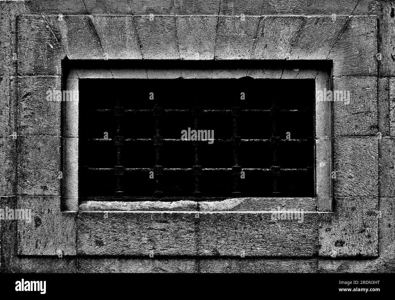 Ein großes versperrtes Gefängnisfenster in einer Steinmauer. Stockfoto