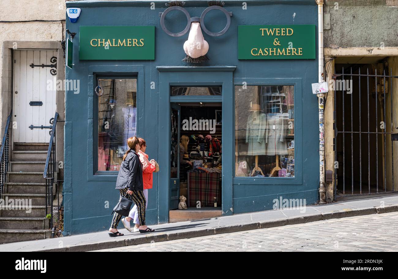 Frauen gehen vorbei an einem schrulligen Bekleidungsgeschäft mit Scherzgläsern, Grassmarket, Edinburgh, Schottland, Großbritannien Stockfoto