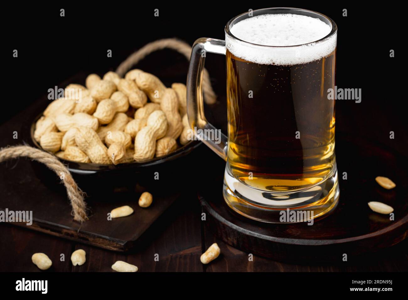 Eine Tasse Bier mit Schaum und Erdnüssen im Hintergrund Stockfoto