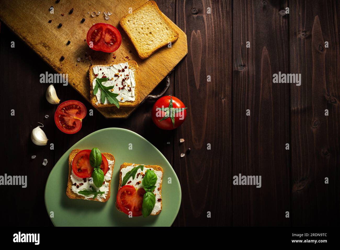 Köstliche Sandwiches mit Frischkäse mit Tomatosalz und pepe auf dunklem Holzhintergrund Stockfoto